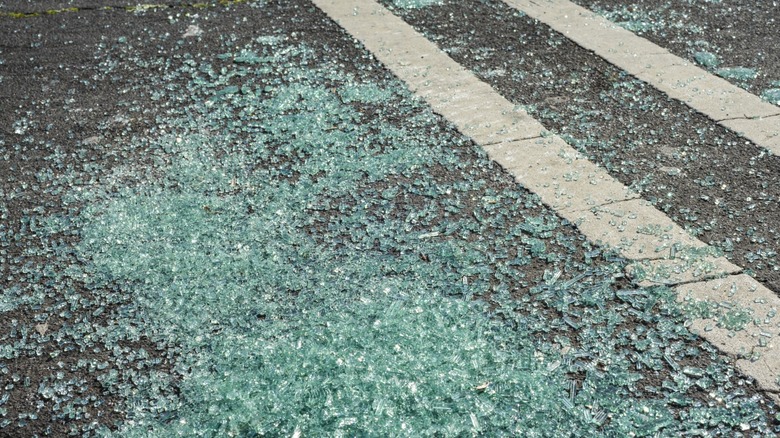 Many broken shards of glass on a road marked with two white lane lines