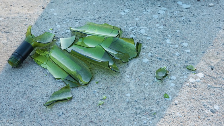 Big shards of a broken green glass bottle littered on the ground
