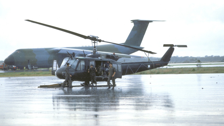 Service members outside helicopter in the rain.