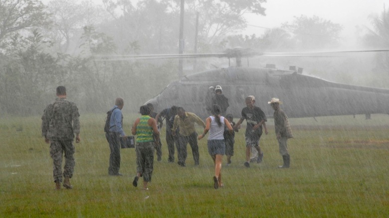 People departing and approaching US Navy helicopter in the rain.