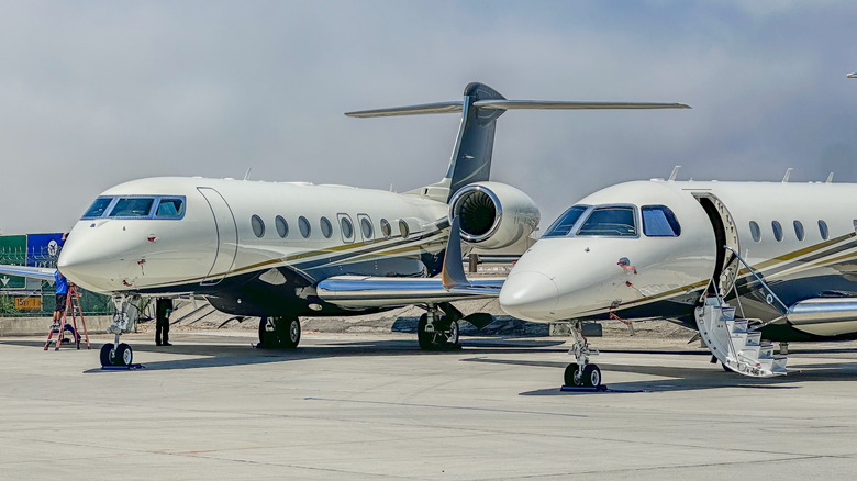 Two private jets parked at an airport.