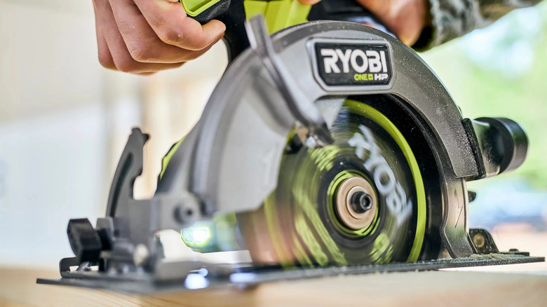 A person using an 18V Ryobi circular saw.