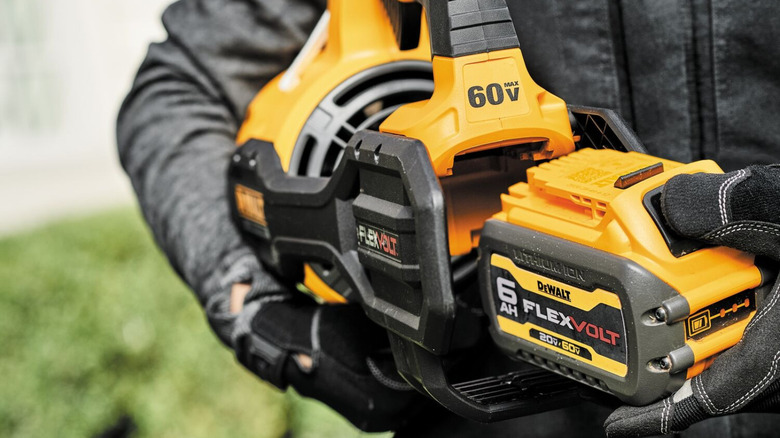 Hand sliding DeWalt FLEXVOLT battery into DeWalt power tool