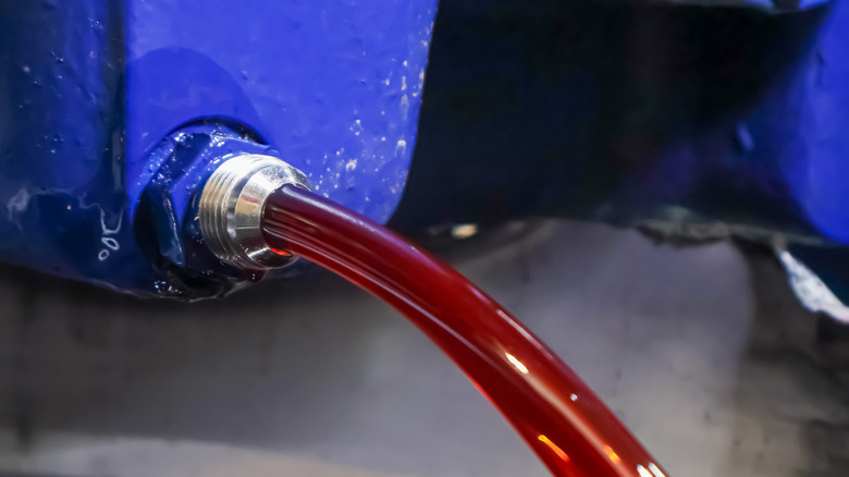 Red transmission fluid pouring through drain plug