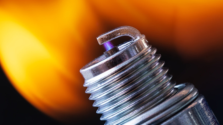 Close-up of a spark plug tip with a spark between the electrodes