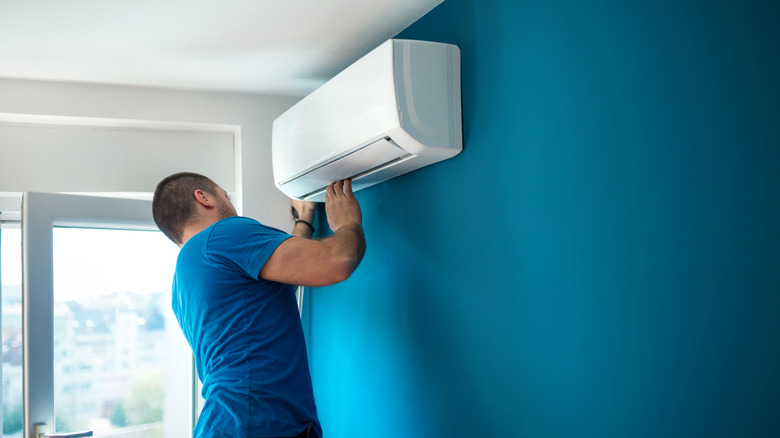 Man in blue shirt installing A/C unit