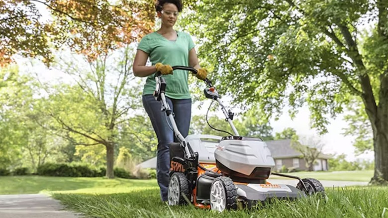 A woman pushes a Stihl battery-powered lawn mower