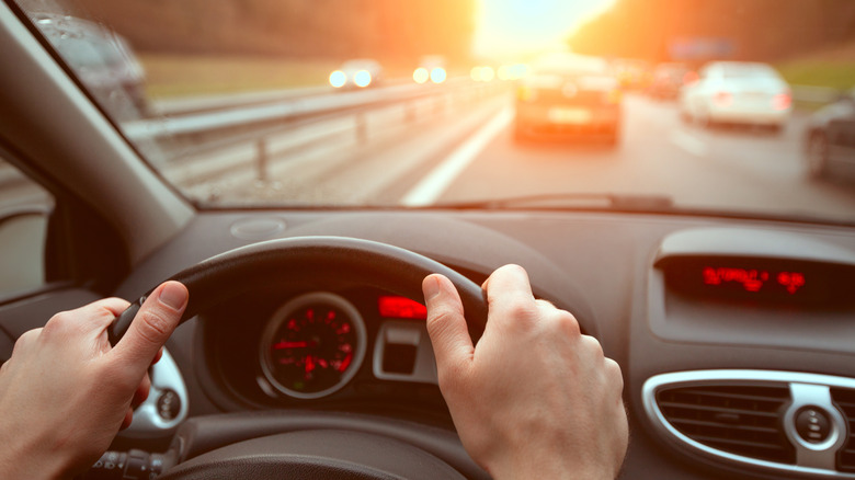 A driver using both hands to grip the wheel while driving on a highway.