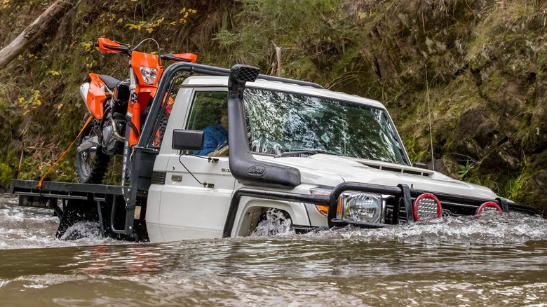 a toyota truck drives in water with a safari snorkel