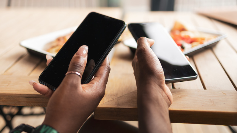 two people holding phones nearby