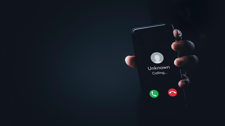 Hand holding mobile phone with unknown caller notification