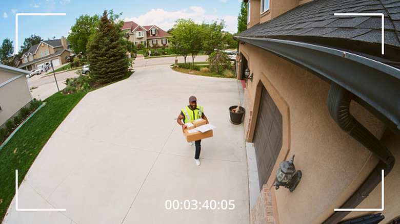 Packages being delivered to a home, as seen through the lens of an outdoor security camera.