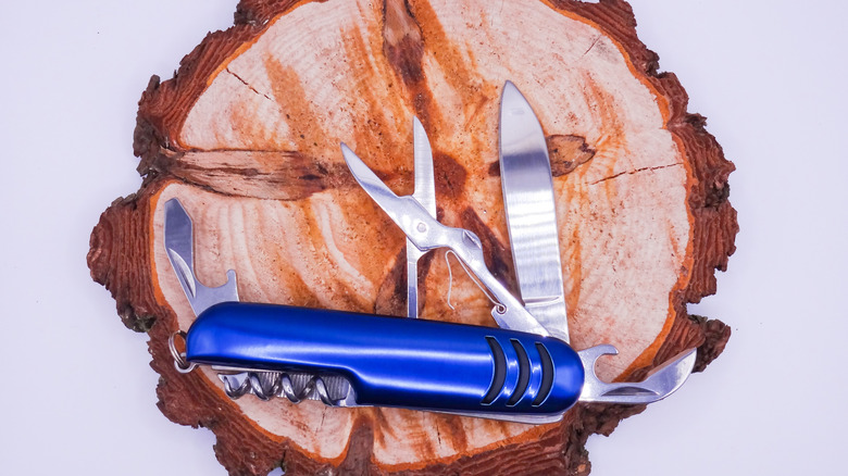 A Swiss army knife opened on a piece of wood.