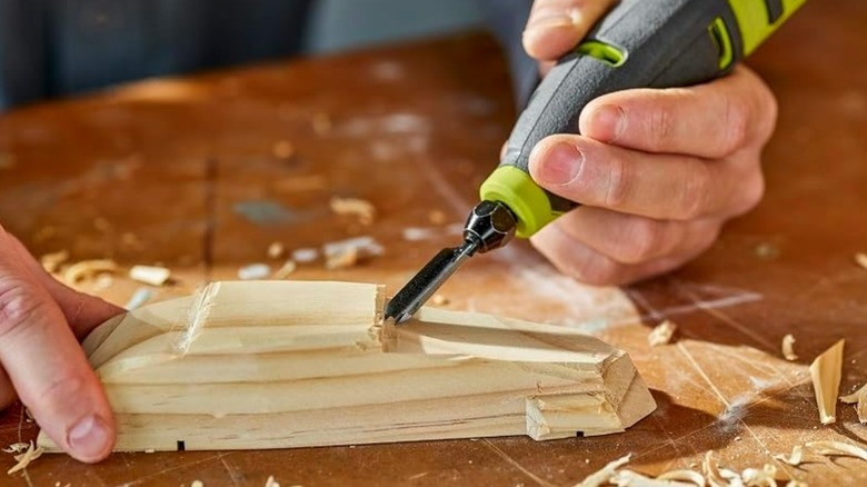 A person using a Ryobi wood carver power tool.