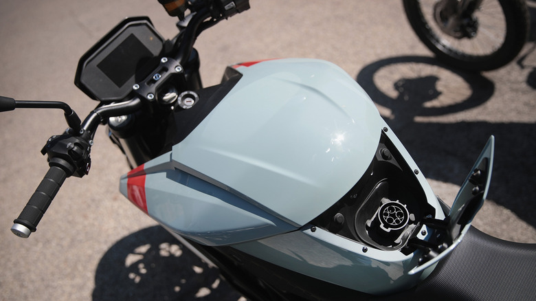 A charging port of an electric motorcycle with a pastel blue tank