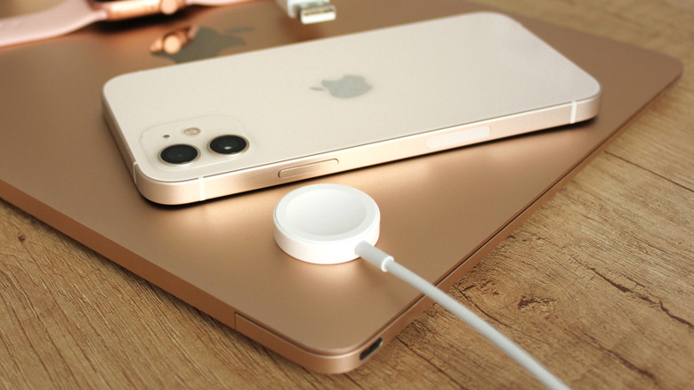 Apple Watch charger and iPhone on a MacBook