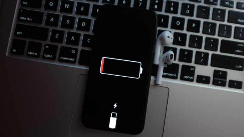 iPhone on a MacBook keyboard showing low battery icon