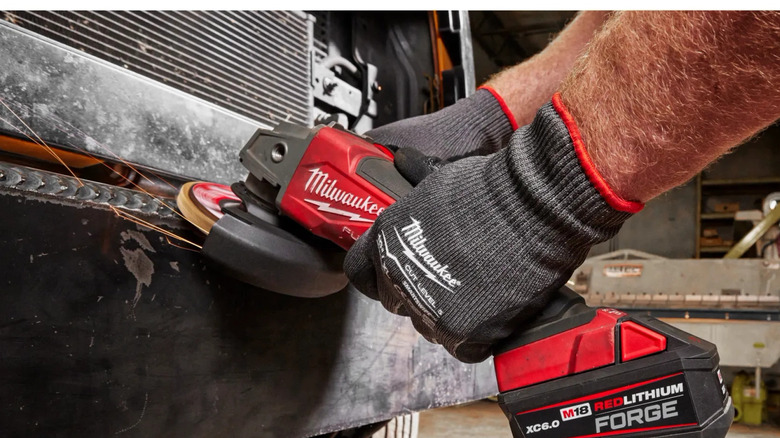 A person using a Milwaukee angle grinder with an M18 Forge battery