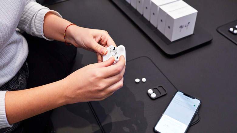 Woman holding AirPods with iPhone on table