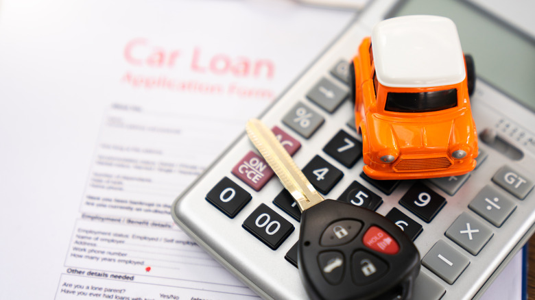 A car key on a car finance agreement and calculator
