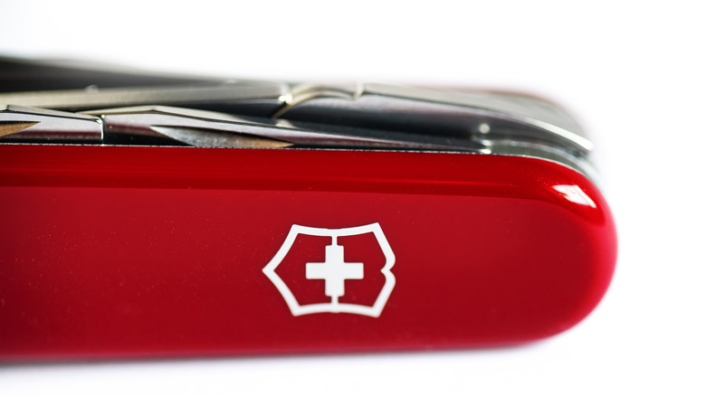 A red Swiss army knife with close-up logo on white background.