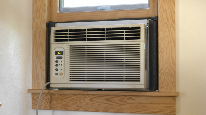 An air conditioner set up in an unstained wooden window frame