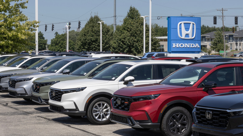 A line of Honda CR-Vs parked on lot at Honda dealership.