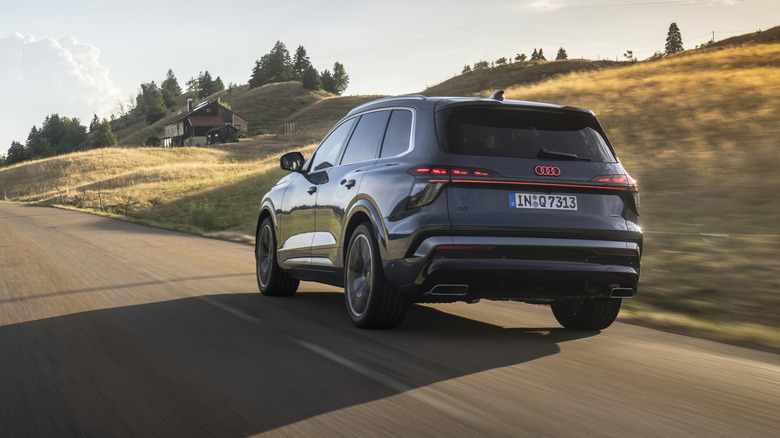 The new Audi Q7 on the move on a country road, rear 3/4 view