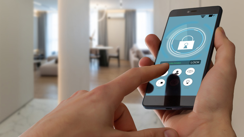 Smart home automation app on smartphone held by a person with home interior in the background
