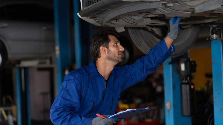 Mechanic inspecting underside of vehicle