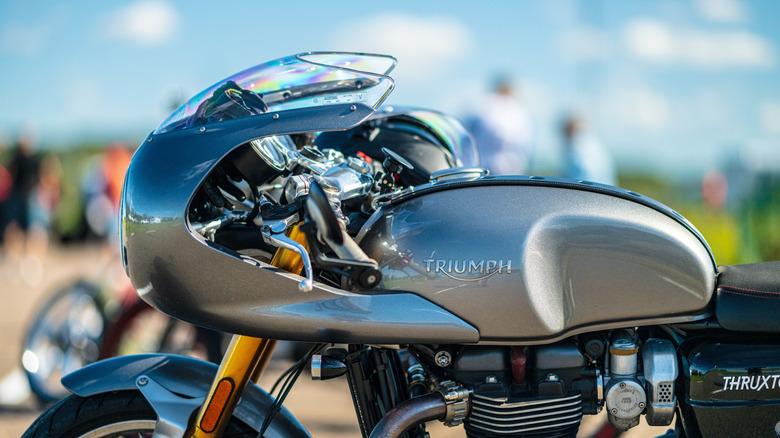 A close-up side shot of a gray Triumph Thruxton's fuel tank and stylized front fairing