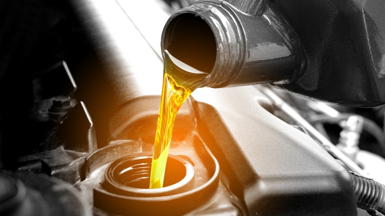 a closeup image of someone pouring oil into their car's engine