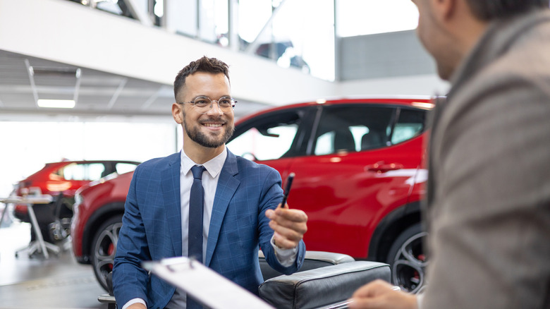 Car salesman and customer signing a new deal