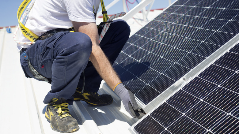 A worker installs solar panels on a rooftop