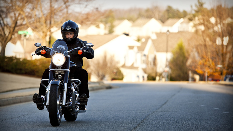 A short rider wearing helmet on a cruiser motorcycle