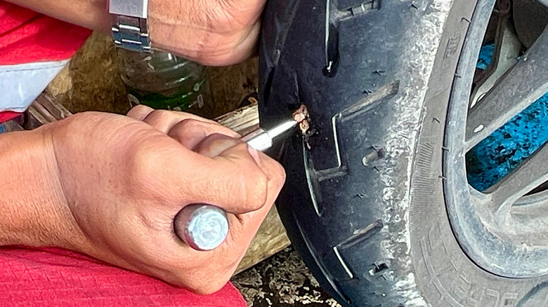A person using a mushroom plug to repair a puncture in a tubeless tire