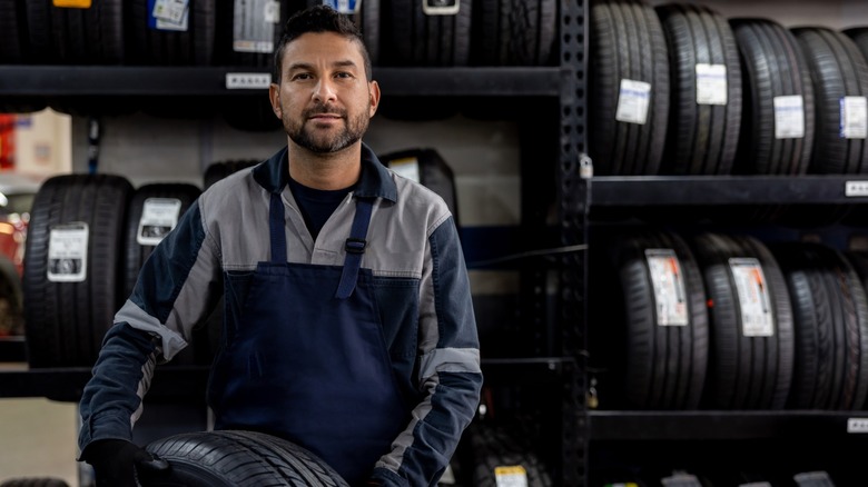 A tire technician carrying a tire.