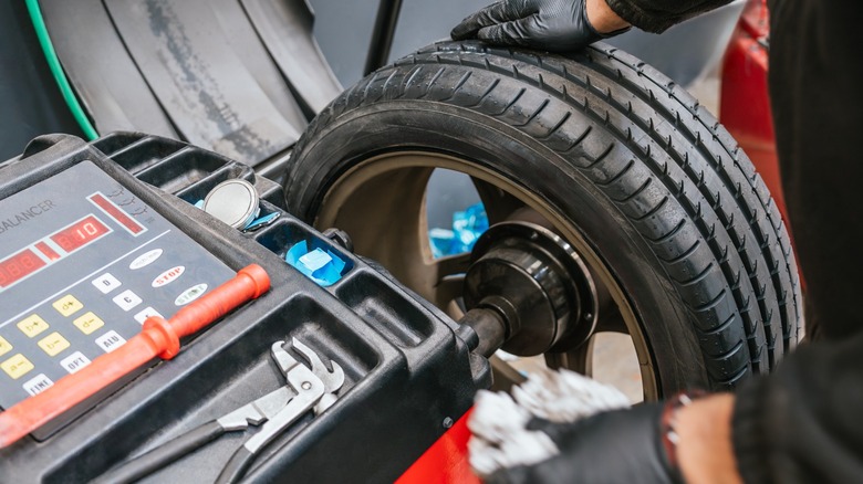 A technician using a machine to balance a tire.