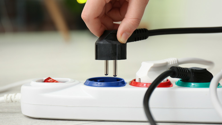 hand plugging in a cable into a power strip