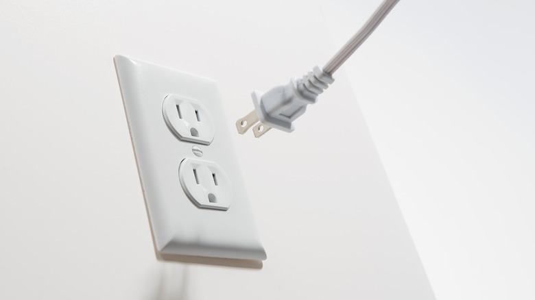Two prong plug being plugged into a three prong outlet