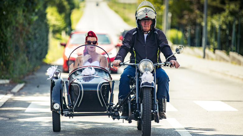 Bride riding to wedding ceremony in an old sidecar motorcycle.