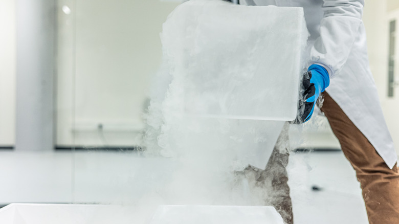 A person lifting dry ice out of a container