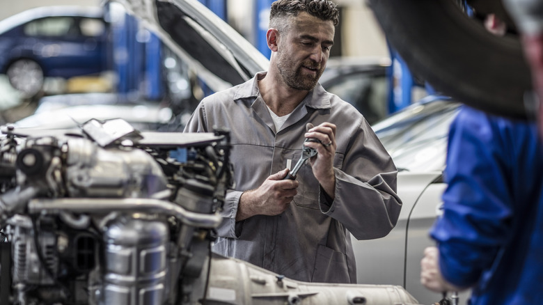 Mechanics servicing complete powertrain removed from car in professional shop
