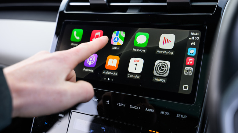 A hand operating Apple CarPlay in a vehicle