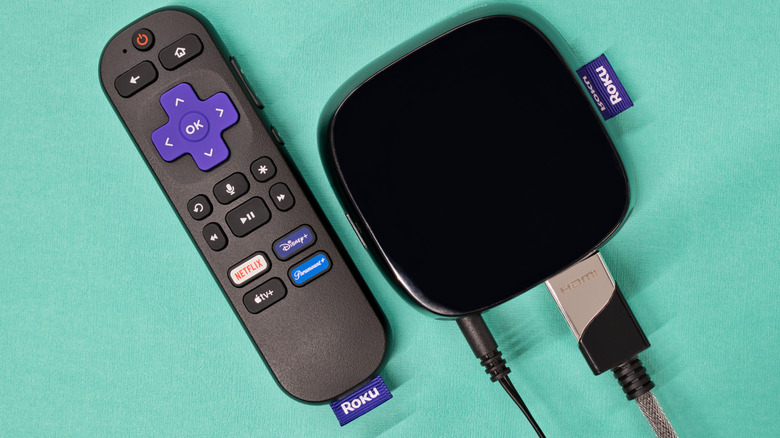 roku remote placed next to the Roku streaming player against a green background