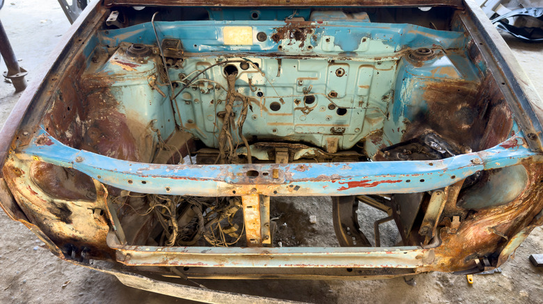 Rusted car frame with engine removed