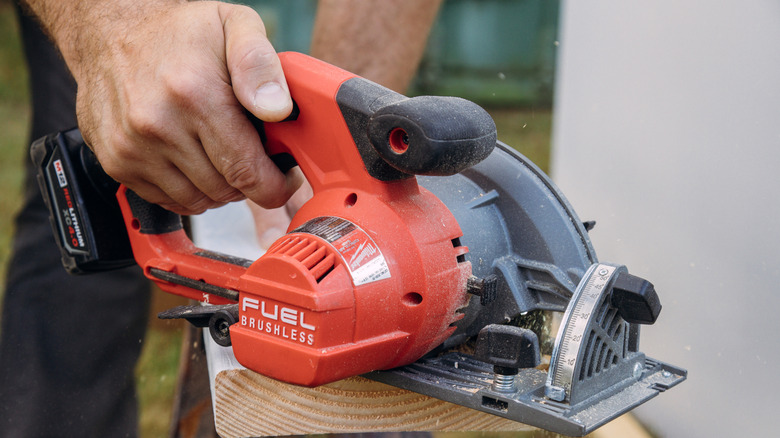 Milwaukee power tool cutting wooden plank