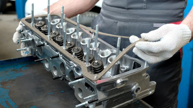 A mechanic preps a cylinder head for installation.
