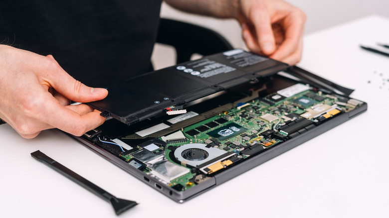 Man holding laptop battery with laptop opened