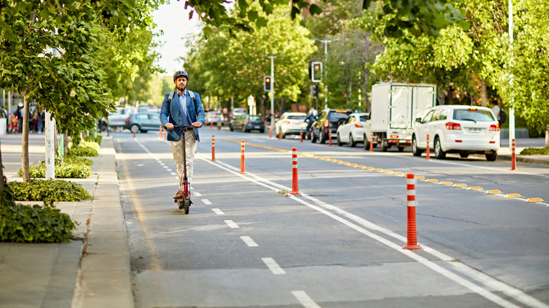 Commuting to work with bicycle. Young business person cycling and riding electric scooter to office in downtown district. Modern diversity people use eco transportation in city. Sustainable lifestyle.